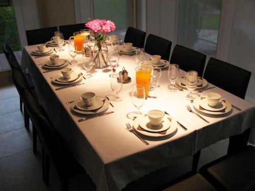 a long table with a white table cloth and glasses and flowers at Guest House Aštuoni in Palanga