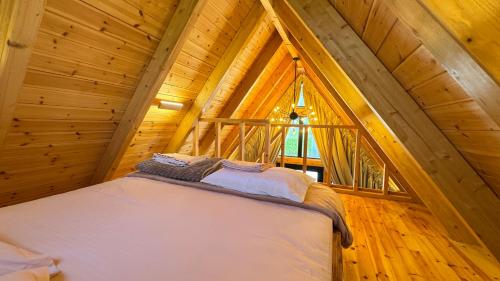 a bed in a wooden room with a window at Konispol Mandarin Cabin in Mursi