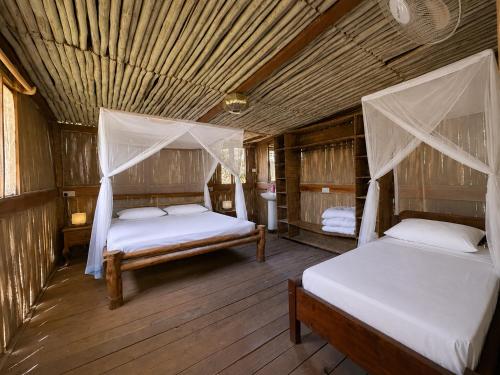two beds in a room with wooden floors at Stay Social Diani - Backpackers & Social Hub in Diani Beach