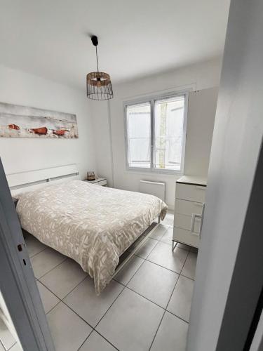 a white bedroom with a bed and a window at Maison 1 chambre in Hyères