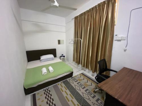 a small room with a green bed and a desk at Homestay Plaza in Temerloh