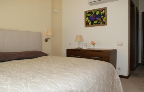 a bedroom with a bed and a dresser and a painting at Guest House Aštuoni in Palanga