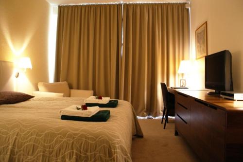 a hotel room with a bed and a desk with a television at Guest House Aštuoni in Palanga