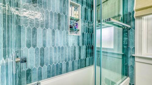 a bathroom with green tiled walls and a glass shower at Shore Escape Steps to the Beach in Ventnor City