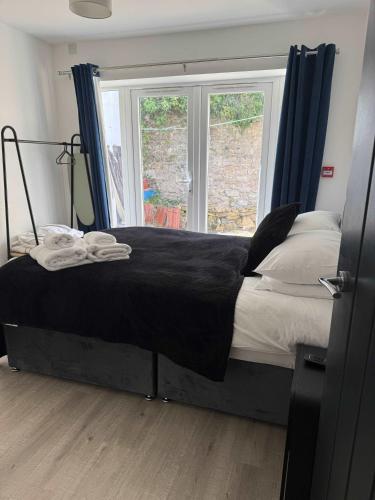 a bedroom with a bed with blue curtains and a window at Ground Floor Flat with Courtyard garden in Weston-super-Mare