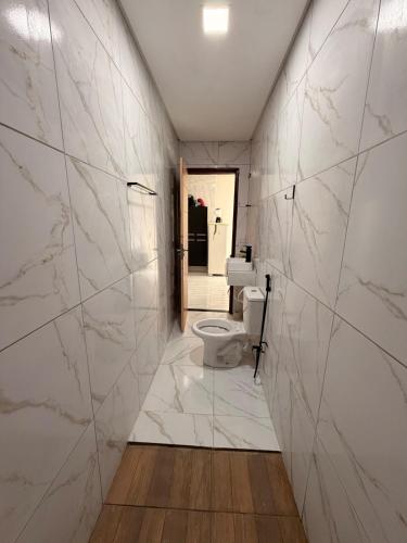 a bathroom with white marble walls and a toilet at Comfort Ton House in Juazeiro do Norte