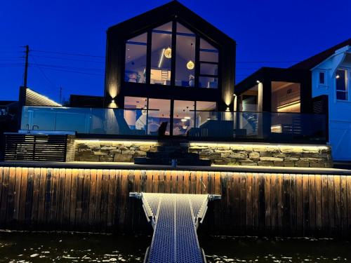 a house on the water at night at OceanView Karmoy Jacuzzi, Sauna & Sea Views in Karmøy