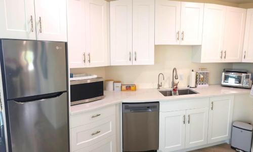 a kitchen with white cabinets and a stainless steel refrigerator at Lake View Escape! in West Kelowna