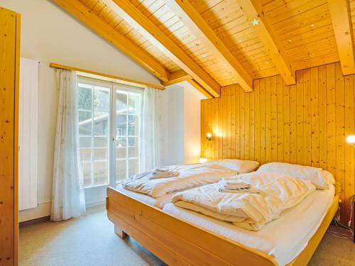 a bed in a room with a large window at Sonniges Chalet mit fantastischem Bergblick in Lenk