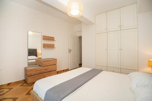 a white bedroom with a bed and a mirror at Blue Veranda Apartment in Pera Gyalos