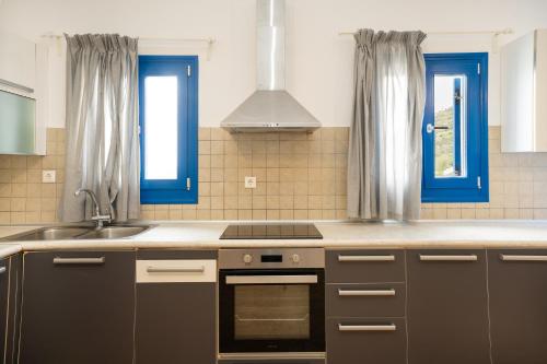 a kitchen with a sink oven and blue windows at Blue Veranda Apartment in Pera Gyalos