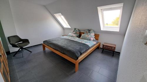 a bedroom with a bed with a chair and a window at Nordmannsland I in Sudermarsch