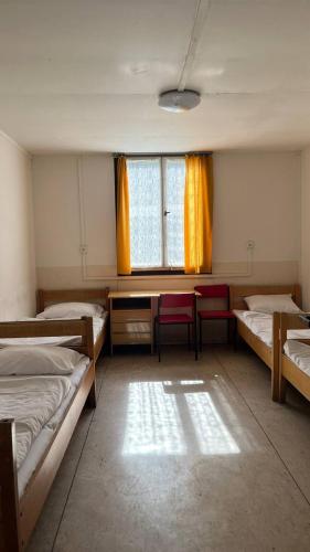 a room with three beds and a table and a window at Wellness & Nature Hostel in Pirkenhammer