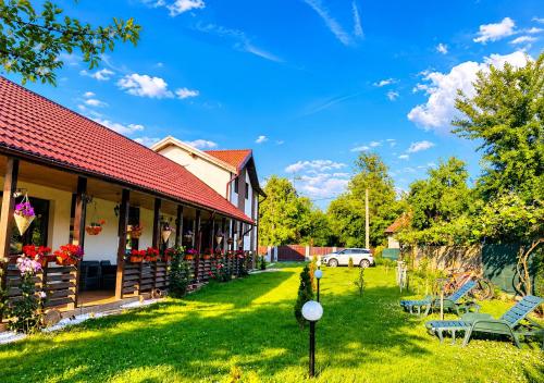 a house with a red roof and a yard at Serenity Garden Villa in Runcu