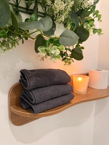 a wooden shelf with a pile of towels and a candle at Escale Confort A1-2 Chambres Stationnement Facile in Roye