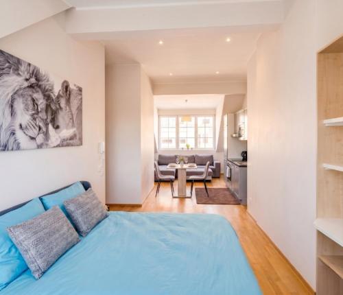a bedroom with a blue bed and a kitchen at Pétrusse Élite Suites - Elegant Suites Luxembourg City Center in Luxembourg