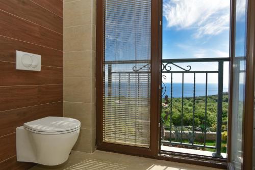 a bathroom with a toilet and a large window at Vila sa bazenom Emar, Budva in Krimovice