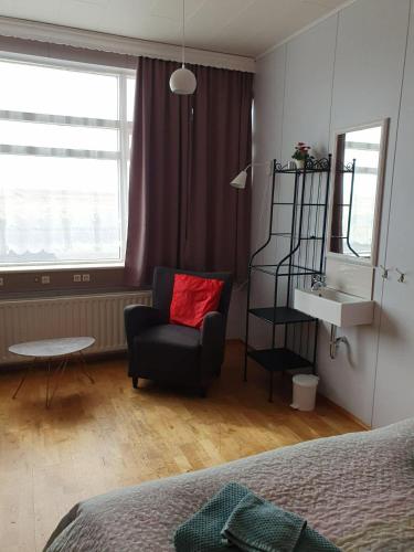 a bedroom with a chair and a table and a window at Guesthouse Langafit in Laugarbakki