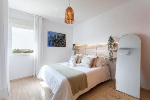 a white bedroom with a bed and a window at Apto Oasis Playa & Golf Almerimar in Almerimar