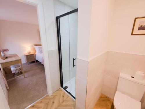 a bathroom with a glass shower door next to a bedroom at Kestrel Lodge - hot tub , sauna, EV and bike storage in Aviemore