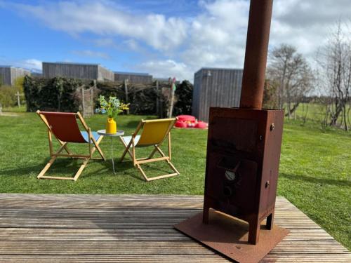 two chairs and a table on a deck next to a stove at Sinne - Ecohuisjes Terschelling in Midsland