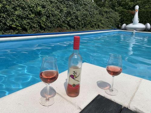a bottle of wine and two glasses next to a swimming pool at La dolce vita in Novi Banovci
