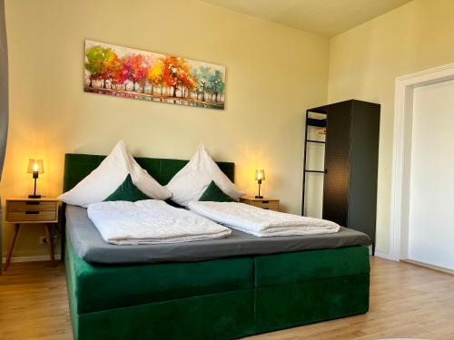 a bedroom with a green bed with two pillows at Apartments am Burgberg in Bad Harzburg
