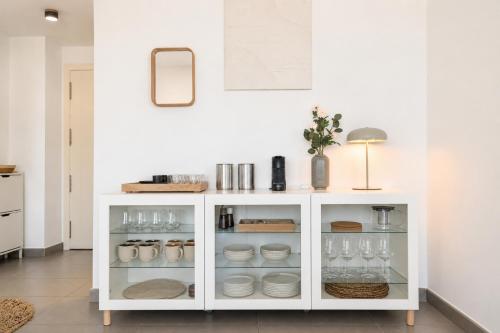 a white cabinet with dishes and wine glasses at Altea Sol Marina Apartment by NRAS in Altea