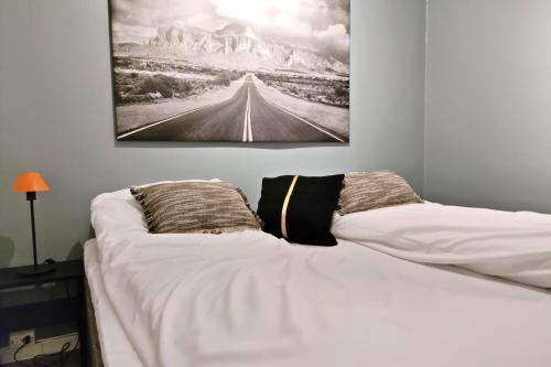 a white bed with two pillows and a painting on the wall at Lofotenfeeling, Haverringen Panorama in Vestvågøya