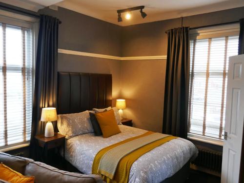 a bedroom with a bed and two windows and a couch at Dewsbury House in Blackpool