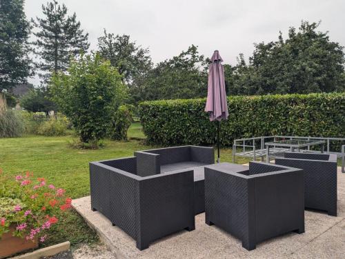 a patio with an umbrella and chairs and a table with an umbrella at L'échappée Dervoise in Montier-en-Der