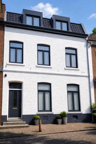 a white house with black windows on a street at B&B Saint Pierre in Maastricht