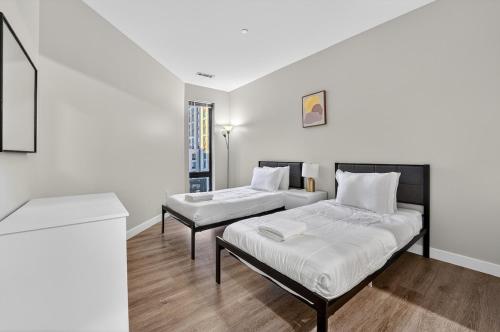 a white room with two beds and a table at Spacious & Modern 2BR 2BA unit in assembly square in Somerville