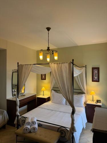 a bedroom with a canopy bed and a sink at Evzin Hotel in Kato Loutraki