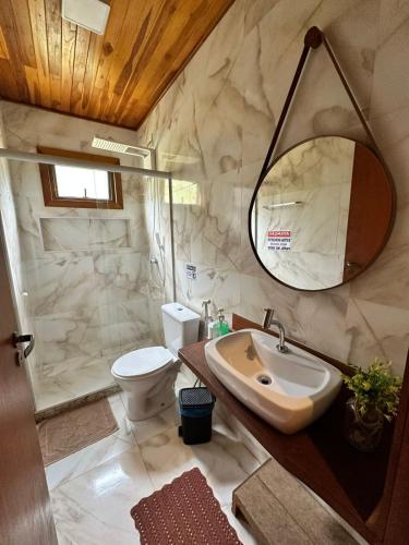 a bathroom with a sink and a toilet and a mirror at Rancho Nosso Lago in Domingos Martins