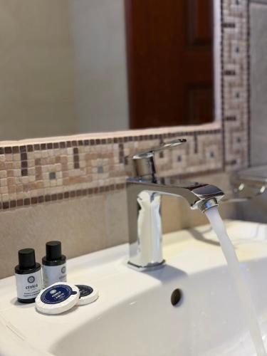 a bathroom sink with a faucet and a mirror at Evzin Hotel in Kato Loutraki
