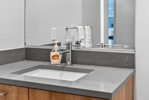 a bathroom sink with a bottle of soap on it at Spacious & Modern 2BR 2BA unit in assembly square in Somerville