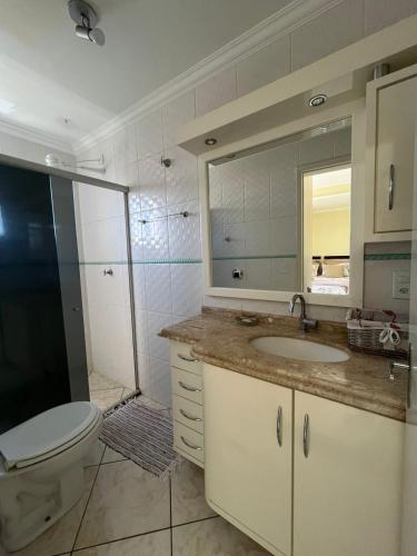 a bathroom with a toilet and a sink and a mirror at Apto no Centro de Guaíra com ar condicionado na sala e quarto in Guaíra