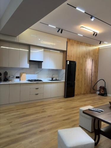 a large kitchen with white cabinets and a black refrigerator at Jamshed apartment in Samarkand