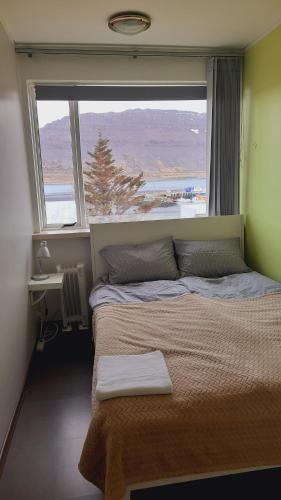 a bedroom with a bed with a large window at Fjord Guesthouse in Súðavík