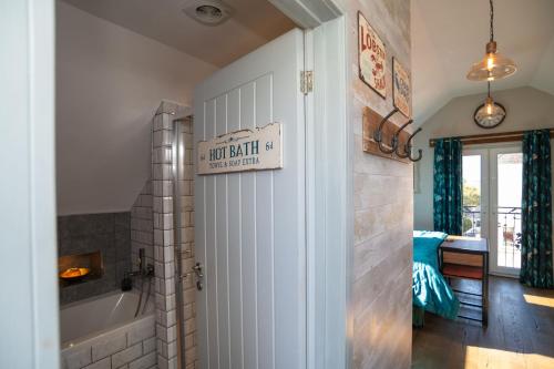 a bathroom with a tub and a door with a sign on it at Garden View Apartment in Salcombe