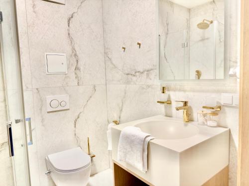 a white bathroom with a sink and a toilet at Luxury Rooftop Apartment LEGRAND in Vienna