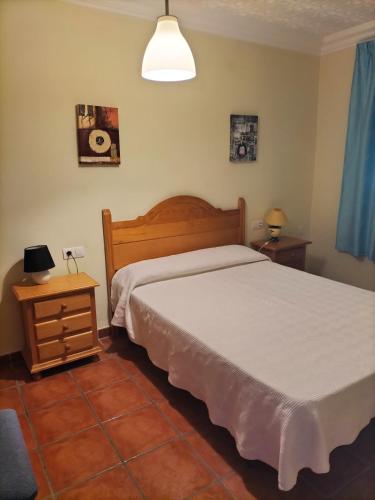 a bedroom with a bed and two tables and a lamp at Casa Detrés in Cogollos de Guadix