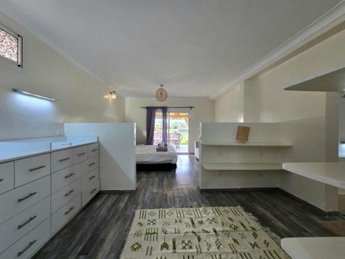 a large kitchen with white cabinets and a bed at Admylla in Sraghna