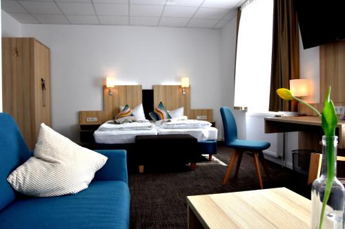 a hotel room with two beds and a blue couch at Seehotel Zum Löwen in Strasen