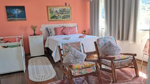 a room with a bed with chairs and a table at Pousada Aconchego dos Puris in Resende