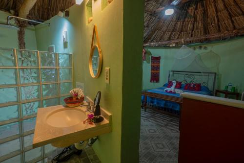 ein Badezimmer mit Waschbecken und ein Bett in einem Zimmer in der Unterkunft The Pickled Onion Hotel & Restaurant Uxmal in Santa Elena