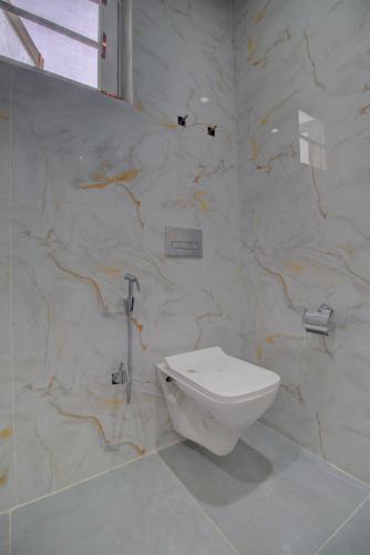 a bathroom with a toilet and a marble wall at Royal Cliff Resort Pahalgam in Pahalgām