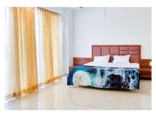 a bedroom with a bed and a window with curtains at Prachi Shree Hotel and Resort in Badnāwar