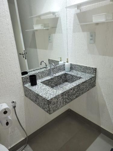 a bathroom with a granite sink with a mirror at Diamond - Flat Bela Estância in São Lourenço